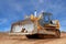 Heavy bulldozer with half raised blade in sandpit