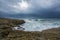 Heavy clouds with stormy waves beating against rocks and cliffs