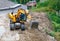 A heavy construction excavator works at a construction site to widen the carriageway