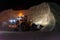 Heavy construction and mining machinery filling the bucket of a stockpile during the night shift