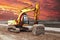 A heavy crawler excavator with a large bucket is getting ready for work against the sunset. Beautiful view of the excavator