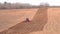 A heavy crawler tractor plows and buries a field in early spring, a plowed field for crops.