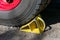 Heavy-duty yellow metal chock under the wheel of trailer with handle for easy removal. Wheel chock helps keep the truck in place