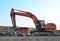 Heavy excavator working at gravel quarry unloads old concrete stones for crushing and recycling to gravel or cement.