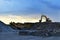 Heavy excavator working in quarry on a background of sunset and blue sky.