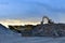 Heavy excavator working in quarry on a background of sunset and blue sky.