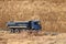 A heavy four-axle dump truck of blue drives along a dirt road against the background of a clay embankment. Career and road works.