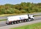 Heavy fuel tanker truck by GAZPROM driving on highway. Transportation of liquid goods. Metal chrome cistern with petrochemicals