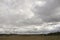 Heavy grey clouds in the cold autumn sky over fields, forests and mountains