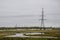 Heavy grey clouds in the cold autumn sky over green fields, trees, forests, streams. Before storm. Electric poles