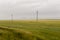 Heavy grey clouds in the cold autumn sky over green fields, trees, forests, streams. Before storm. Electric poles