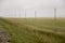 Heavy grey clouds in the cold autumn sky over green fields, trees, forests, streams. Before storm. Electric poles