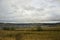 Heavy grey clouds in the cold autumn sky over  village with small houses far away in the mountains and fields. Travelling. People