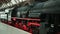 Heavy industrial steam locomotive train red and black engine wheels is at the railway station.