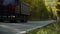 Heavy Laden Dump Trucks Drive in a Mountainous Wooded area on an asphalt Road on an Autumn Sunny Day