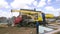 Heavy machinery and the crew of male carpenters at the construction site. Clip. Rear view of workers and machinery on