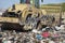 Heavy machinery shredding garbage in an open air landfill. Pollution