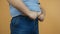 Heavy man trying to fasten jeans pants under a fat stomach, the problem of overeating, obesity