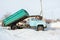 Heavy old blue dump truck with raised body close-up on the background of a snowy road, side view