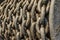 Heavy, old chain of a crane for ship loading rolled up on drum with selective focus