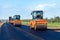 Heavy orange road rollers compacts the bitumen layer of newly laid asphalt. Reconstruction of a roadway