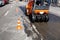 Heavy orange vibratory road roller compacts asphalt on the repaired part of the cityâ€™s road