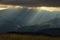 Heavy overcast sky with sunrays over meadows and colorful forests at autumn, mountain Goc