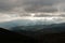 Heavy overcast sky with sunrays over meadows and colorful forests at autumn, mountain Goc