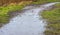 Heavy rain drops splashing onto a flooded dirt footpath through