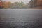 Heavy rain on the lake with autumn trees on the shore