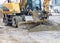 A heavy road excavator smooths a pile of rubble with a bucket at a construction site