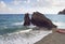 Heavy rock in the Mediterranean, by a beach with a red lifeboat.