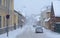 Heavy snowfall in city, some pedestrians and cars on the street