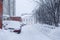 Heavy snowfall, frost and blizzard in the city. A thick layer of snow on the roads and cars in the parking lot. The problem of