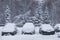 Heavy snowfall, frost and blizzard in the city. A thick layer of snow on the roads and cars in the parking lot. The problem of