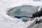 Heavy snowfall. The snowdrifts on the roof of a car. A man cleans the windshield from the snow