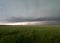 Heavy Storm Clouds Over an Agricultural Field with Wind Turbines and a Summer Crop