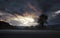 Heavy storm clouds at sunset with tree on meadow