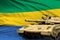 Heavy tank with fictional design on Gabon flag background - modern tank army forces concept, military 3D Illustration