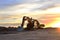 Heavy tracked excavators at a construction site on a background  sunset.