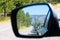 Heavy traffic jam, two-lane highway, mountain scenery on horizon and blue sky reflection in car rearview mirror