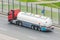 Heavy truck with a tank for flammable liquids rides on the road, back view