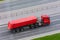 Heavy truck with trailer and bulk cargo - soil, gravel, sand covered with a rubber tent fabric rides on the highway in the city