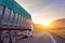 Heavy truck with a trailer for cargo, goods rides on a mountain highway, against the background of the evening sky a bright sunset