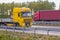 Heavy trucks move along rural road.