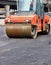 A heavy vibratory roller compresses hot asphalt in the working area of the roadway