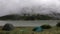 Heavy white clouds over a tourist tent near the lake, rainy weather.