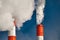 Heavy white steam clouds rise over chimneys of plant