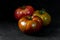 Heirloom tomatoes. Three tomatoes of different colors on a black textured background