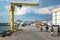 Hel, Poland - 08.01.2021: People walking and cycling under yellow ship loading crane in the port of Hel on a nice warm